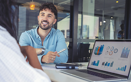 Photo of a woman sitting on a bench with a coffee and looking at a tablet