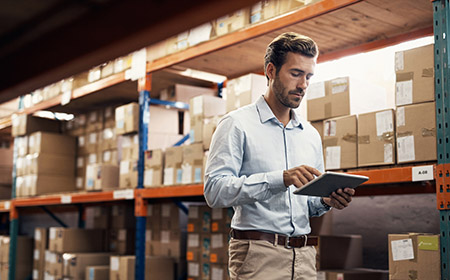 Photo of a a man using a tablet in a warehouse