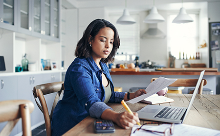 Photo of two hands working at a laptop next to a coffee.