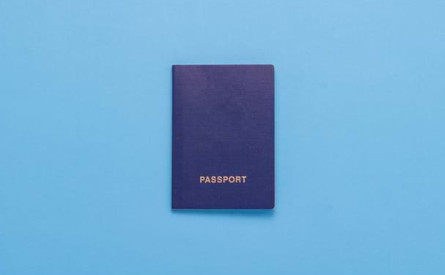 Photo of a generic blue passport on a light blue surface.